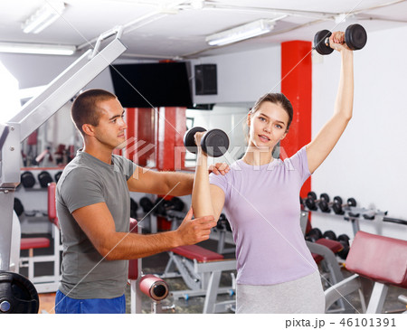 Instructor helping woman with dumbbells Instructor helping woman with dumbbells 46101391