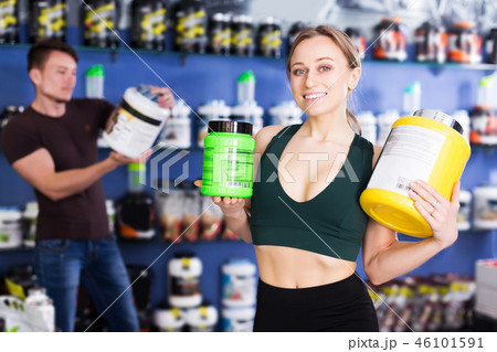 sporty woman holding big cans of sport nutrition 46101591