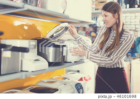 Young positive female housewife choosing multicooker Young positive female housewife choosing multicooker 46101698