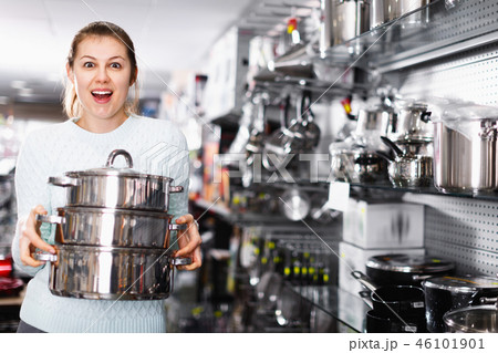 Woman is choosing saucepan for her house in the store. Woman is choosing saucepan for her house in the store. 46101901