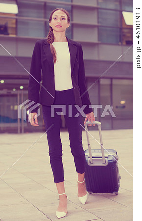 Adult businesswoman in suit with suitcase is staying near the building 46101913