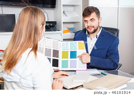 Competent seller in showroom helping young female client to choose furniture materials for her apartment 46101914