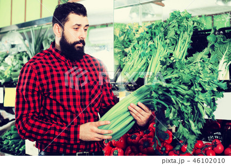 Shop assistant demonstrating celery Shop assistant demonstrating celery 46102010