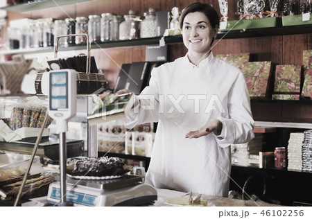 Shop assistant using scales for festive cake Shop assistant using scales for festive cake 46102256