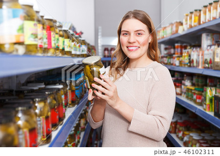 Positive woman customer holding pickle goods in food store Positive woman customer holding pickle goods in food store 46102311
