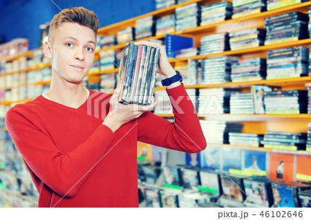 Portrait of positive young male with stack of DVDs in hands Portrait of positive young male with stack of DVDs in hands 46102646