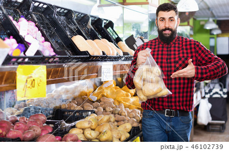 Young male seller offering potatoes Young male seller offering potatoes 46102739