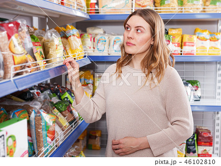 Positive woman buyer choosing groats in grocery food store 46102810