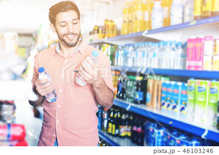 Male choosing bottle with water in supermarket Male choosing bottle with water in supermarket 46103246