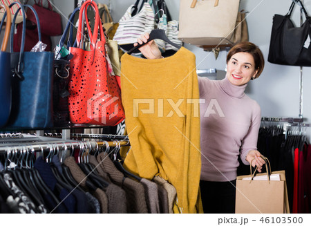 Smiling woman choosing turtleneck sweater 46103500