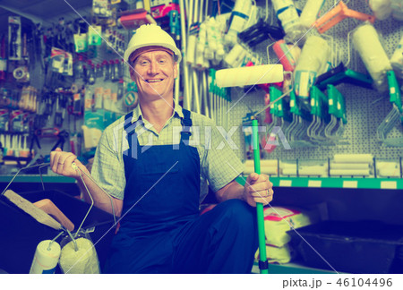 cheerful workman in hardhat buying painting roller cheerful workman in hardhat buying painting roller 46104496