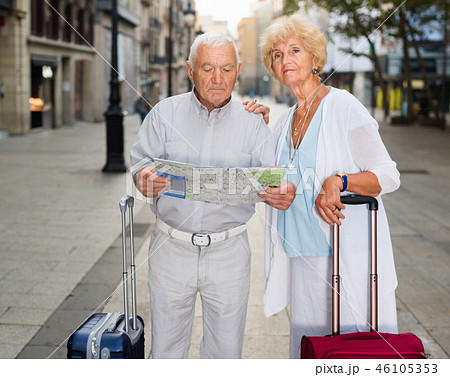 Senior couple of tourists with map and city guide walking 46105353