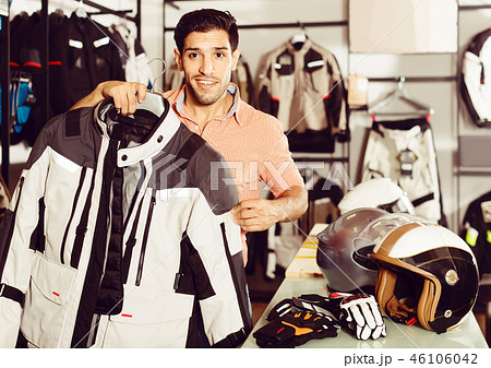 Man is demonstrating new jacket for motorbike in the store. 46106042
