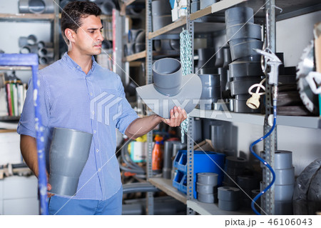 concentrated male is choosing plastic trumpet in the plumbing department in store 46106043