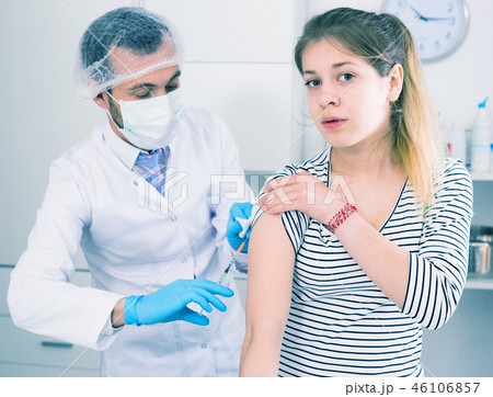 Doctor vaccinating teenage patient 46106857