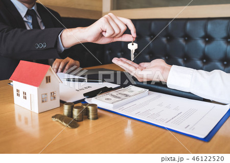 Estate agent giving house keys to client after signing agreement Estate agent giving house keys to client after signing agreement 46122520