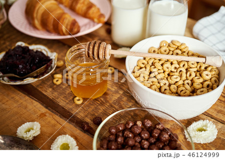 Healthy breakfast with different types of breakfast cereal with honey marmalade croissants and milk 46124999
