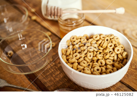 Healthy morning breakfast bowl full of honey flakes with honey dipper and milk on an wooden table Healthy morning breakfast bowl full of honey flakes with honey dipper and milk on an wooden table 46125082