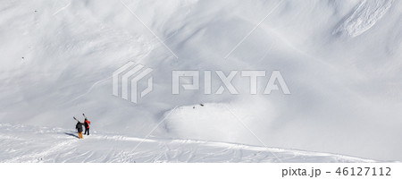Two skiers with skis on his shoulder and slope 46127112