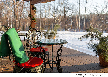 Cast iron chairs and tables with pillows and a blanket on restaurant terrace. Winter landscape of 46129776