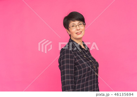 Fashion and people concept - Attractive middle aged woman in glasses over pink background 46135694