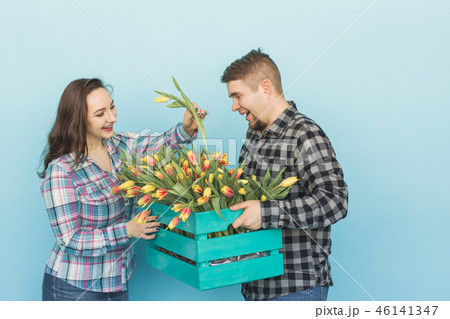Happy florists fixing tulips in a big wooden box on blue background 46141347