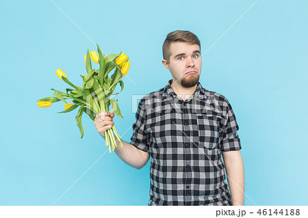 Caucasian handsome man with bunch of yellow tulips on blue background. Caucasian handsome man with bunch of yellow tulips on blue background. 46144188