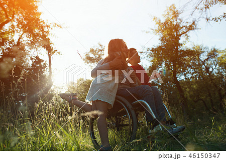 Woman in an armchair has fun with her husband and two children in park 46150347