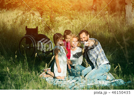 Happy family taking selfie on the picnic in park. Paraplegic 46150435
