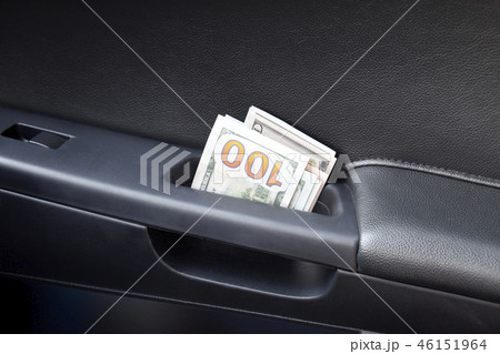 Several notes of US dollars and are folded in half in the door handle of the car. The money in the 46151964
