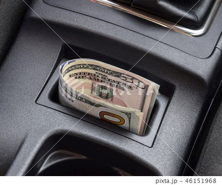 Several banknotes American dollars lie in the niche of the central console of the car. The money in 46151968