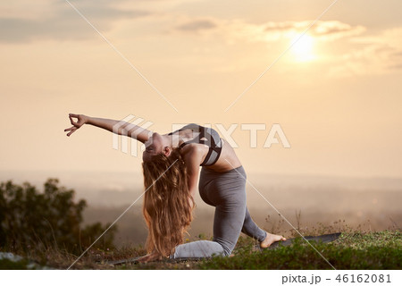 Attractive slim young woman doing yoga exercises outdoors on copy space background of beautiful sky. 46162081