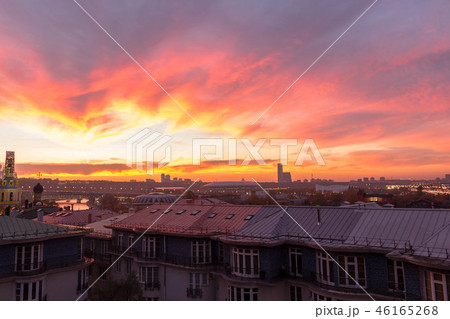 Clouds of beautiful color against the roofs of houses. Sunset pink red orange. Clouds of beautiful color against the roofs of houses. Sunset pink red orange. 46165268