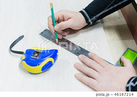 Close up Carpentry, mans hand using tape measure to measure wood plank and marking it with pencil 46167214