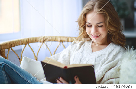 happy young woman reading a book by window 46174035