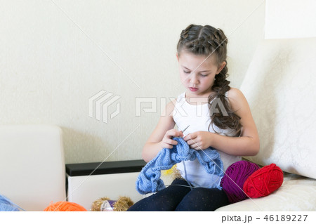 The girl knits with knitting and thread. 46189227