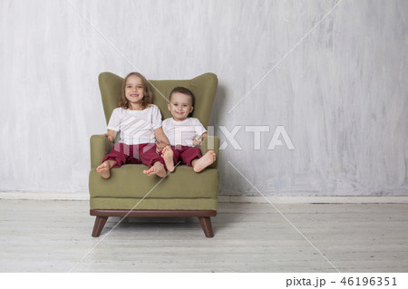little boy and girl are brother and sister sit on a green Chair little boy and girl are brother and sister sit on a green Chair 46196351