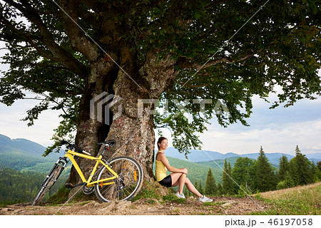 Attractive female cyclist with yellow mountain bicycle, enjoying sunny day in the mountains 46197058