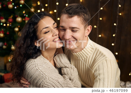 young couple is in christmas decoration and lights young couple is in christmas decoration and lights 46197099