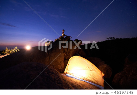 Camping at night on rock formation. Tourist tent and woman doing yoga on mountain top Camping at night on rock formation. Tourist tent and woman doing yoga on mountain top 46197248