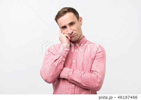 Gloomy man in pink shirt, holding hands on face Gloomy man in pink shirt, holding hands on face 46197466