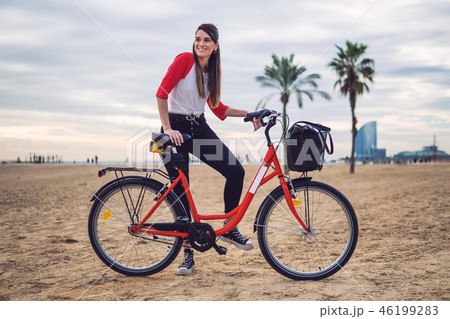 Woman riding bicycle along beach sand at summer time Woman riding bicycle along beach sand at summer time 46199283