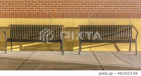 Empty benches against a brick wall on a sunny day 46202549