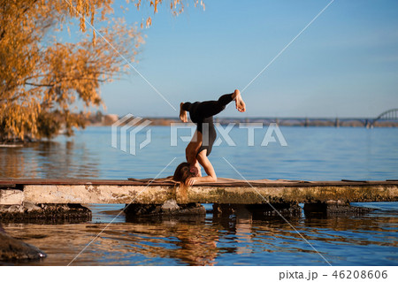 Young woman practicing yoga exercise at quiet pier 46208606