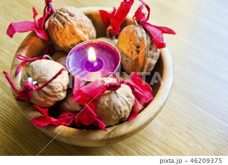 purple candle with decorated wallnuts in a bowl. purple candle with decorated wallnuts in a bowl. 46209375
