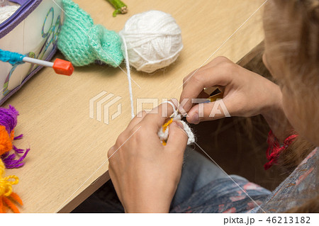 Girl needlewoman knits from threads sitting at the table 46213182