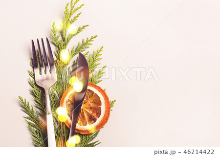Christmas table setting concept. Fork and knife decorated with thuja twig and bokeh lights Christmas table setting concept. Fork and knife decorated with thuja twig and bokeh lights 46214422