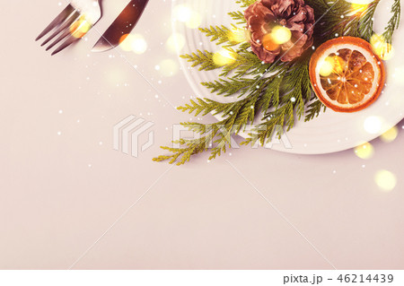 Holiday christmas Plate and cutlery with coniferous twig and dry orange on beige background Holiday christmas Plate and cutlery with coniferous twig and dry orange on beige background 46214439