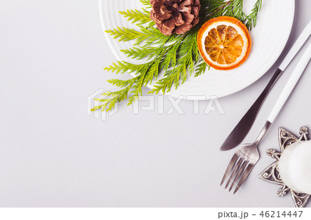 Plate and cutlery decorated with coniferous twig and dry orange. Christmas table setting 46214447