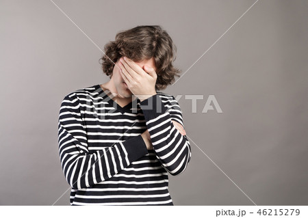 Portrait of upset man covering his face with hand isolated on grey background. Facepalm facial 46215279